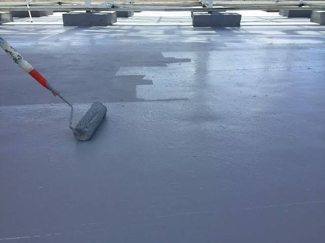 Liquid membrane waterproofing being roller-applied to a concrete deck
